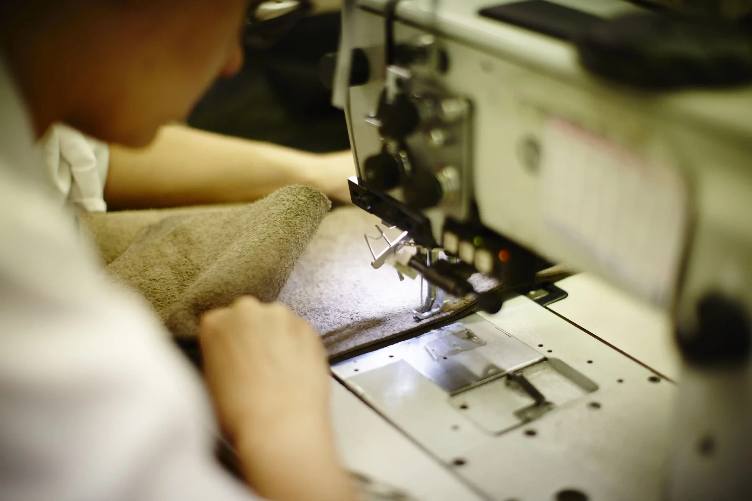 Operaio cuce un rivestimento in pelle con macchina da cucire industriale