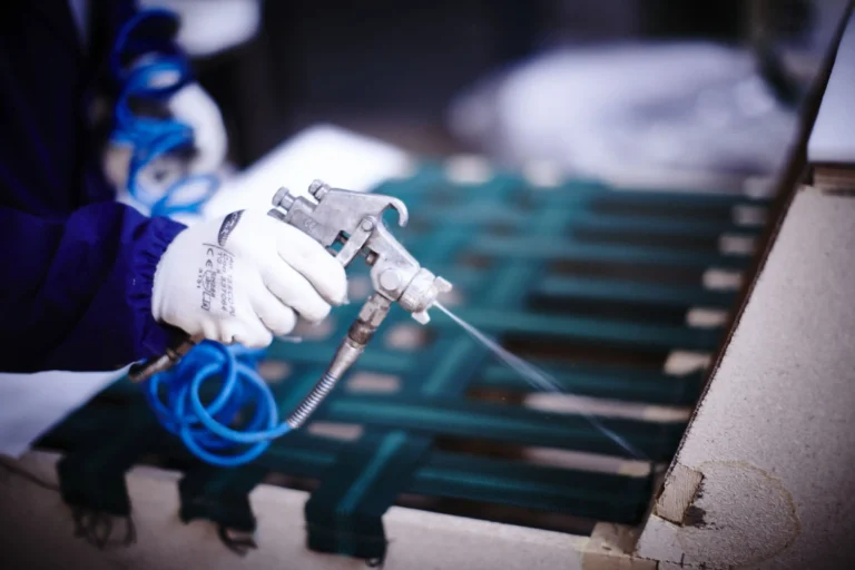 Artigiano spruzza un prodotto sulla struttura in legno di una poltrona