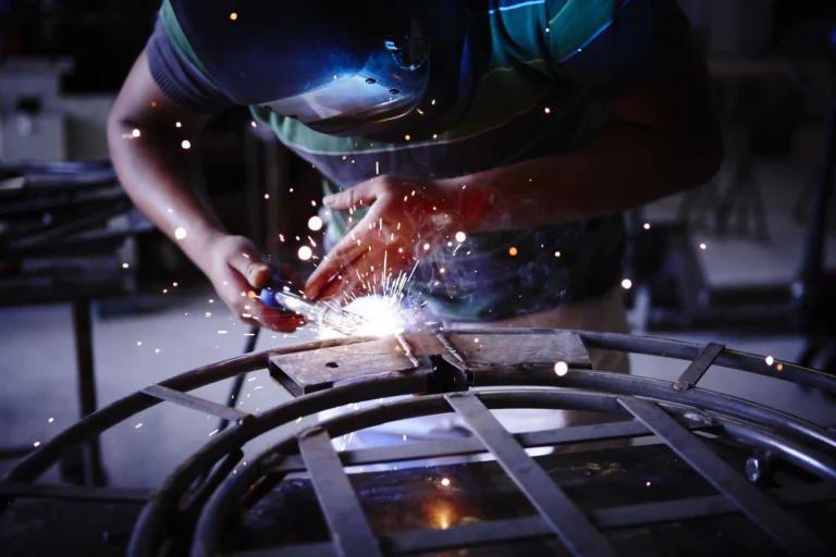 Artigiano mentre salda a mano il meccanismo di una poltrona